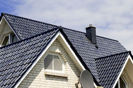In a residential roof, a London roofer replaces damaged tiles and shingles